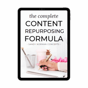 A digital mockup of a tablet displaying the cover of 'The Complete Content Repurposing Formula' by Sandy Norman Concepts. The cover features a workspace with a hand writing in a notebook, a pen holder, a pink coffee cup, and decorative flowers, creating a visually appealing and professional design.